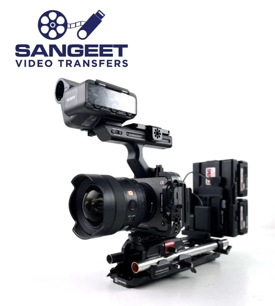 Professional video camera setup with a large lens, on a rig with multiple accessories attached, displaying "Sangeet Video Transfers" logo in the top left corner.